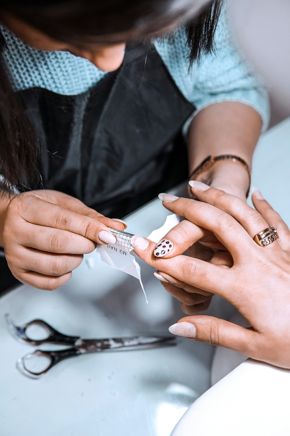 Nail technician applies a paper form to a customer's hand.